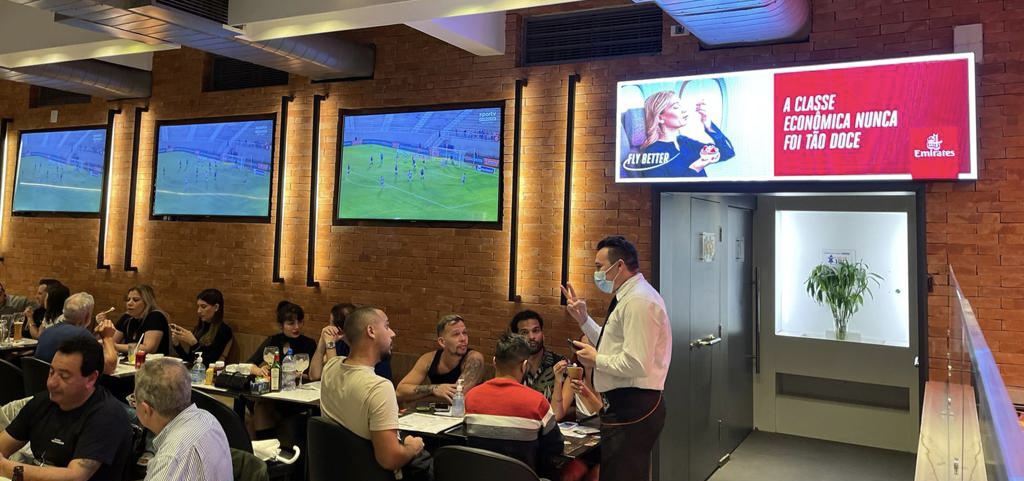 Painel digital com campanha da Emirates em restaurante parceiro da Freeooh
